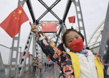 Seorang anak melambai-lambaikan bendera nasional China saat berpose untuk difoto di sebuah jembatan di Harbin, Provinsi Heilongjiang, China timur laut, pada 2 Oktober 2021. Langkah pencegahan dan pengendalian epidemi yang ketat telah diberlakukan di pusat-pusat perbelanjaan utama, objek wisata, dan tempat-tempat lain di kota tersebut yang menjadi titik berkumpulnya masyarakat selama libur Hari Nasional yang sedang berlangsung. (Xinhua/Zhang Tao)