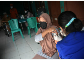Seorang tenaga kesehatan menyuntikkan satu dosis vaksin COVID-19 kepada seorang pria dalam program vaksinasi untuk pengungsi dan pencari suaka di Jakarta pada 28 Oktober 2021. (Xinhua/Zulkarnain)