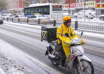 CHANGCHUN, Seorang kurir pengiriman makanan mengantar pesanan daring di Changchun, Provinsi Jilin, China timur laut, pada 9 November 2021. Badai salju yang berkepanjangan sejak Minggu (7/11) mengakibatkan rekor hujan salju di China timur laut. Gelombang dingin itu telah menyebabkan penurunan suhu yang signifikan. (Xinhua/Xu Chang)