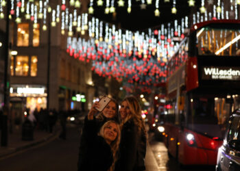 LONDON, Orang-orang berswafoto di Regent Street yang dihiasi lampu Natal di pusat kota London, Inggris, pada 21 November 2021. (Xinhua/Li Ying)