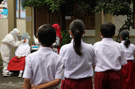 SURAKARTA, Seorang tenaga kesehatan mengambil sampel usap (swab) dari seorang anak perempuan dalam tes asam nukleat COVID-19 bagi siswa sekolah dasar di Surakarta, Jawa Tengah, pada 23 November 2021. (Xinhua/Bram Selo)