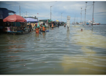 JAKARTA, 9 November, 2021 (Xinhua) -- Orang-orang berjalan melintasi banjir di sebuah pelabuhan di pesisir Jakarta pada 9 November 2021. (Xinhua/Zulkarnain)