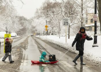 Seorang wanita dan anak-anaknya menyeberang jalan di Evanston, sebelah utara Chicago, Illinois, Amerika Serikat, pada 26 Januari 2021. (Xinhua/Joel Lerner)