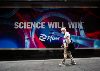 Seorang warga yang mengenakan masker berjalan di depan Kantor Pusat Dunia Pfizer di New York, Amerika Serikat, pada 23 Agustus 2021. (Xinhua/Michael Nagle)