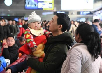Seorang pria yang menggendong anak menunggu kedatangan kereta di Stasiun Kereta Barat Beijing di Beijing, ibu kota China, pada 10 Januari 2020. (Xinhua/Ren Chao)