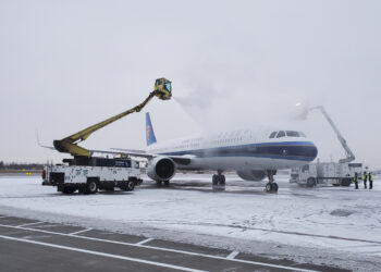 Petugas kru darat membersihkan es dan salju yang menutupi sebuah pesawat di Bandara Longjia di Changchun, Provinsi Jilin, China timur laut, pada 7 November 2021. (Xinhua)