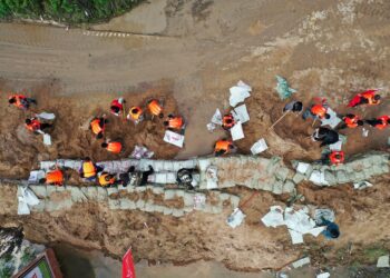 Foto dari udara ini menunjukkan tim penyelamat memperkuat tanggul sementara untuk menahan banjir di Desa Lianbo di Kota Hejin, Provinsi Shanxi, China utara, pada 10 Oktober 2021. (Xinhua/Zhan Yan)