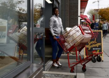 Seorang pelanggan berjalan keluar dari supermarket sembari mendorong keranjang dorong yang dipenuhi barang belanjaan di Washington DC, Amerika Serikat, pada 12 November 2021. (Xinhua/Ting Shen)