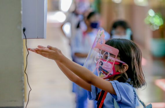 MAKATI CITY, Seorang murid yang mengenakan masker dan pelindung wajah membersihkan tangannya setelah mengikuti simulasi kelas tatap muka di sebuah sekolah dasar di Makati City, Filipina, pada 2 Desember 2021. (Xinhua/Rouelle Umali)