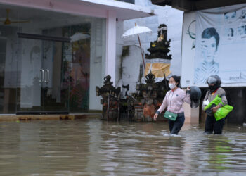 BALI, Orang-orang melintasi jalan yang terendam banjir usai diguyur hujan lebat di Bali pada 6 Desember 2021. (Xinhua/Komang Alfan)