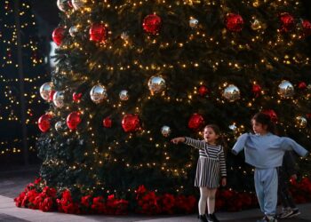 BEIRUT, Anak-anak terlihat di depan sebuah pohon Natal yang dihias di pusat kota Beirut, Lebanon, pada 6 Desember 2021. (Xinhua/Bilal Jawich)