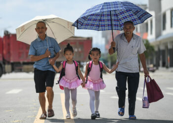 RONG'AN, Dua orang warga lanjut usia menemani cucu perempuan mereka dalam perjalanan ke pusat pelatihan balet di Chang'an, wilayah Rong'an, Daerah Otonom Etnis Zhuang Guangxi, China selatan, pada 15 Juli 2021. Komunitas Rongkang menjadi tempat relokasi untuk pengentasan kemiskinan. Warga hidup dengan damai dan bahagia di tempat itu. (Xinhua/Zhang Ailin)