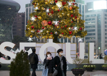 SEOUL, Orang-orang berjalan melintasi pohon Natal yang dihias di Seoul, Korea Selatan, pada 11 Desember 2021. (Xinhua/Wang Yiliang)