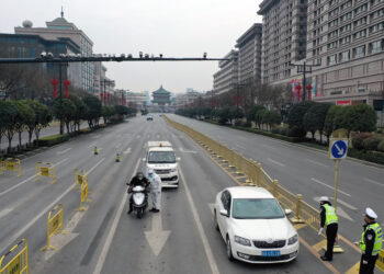 XI'AN, Foto dari udara yang diabadikan pada 27 Desember 2021 ini menunjukkan sejumlah petugas polisi memeriksa kendaraan di Xi'an, Provinsi Shaanxi, China barat laut. Xi'an meningkatkan kebijakan antiepideminya dan menerapkan manajemen tertutup paling ketat mulai Senin (27/12) untuk meredam penyebaran lonjakan terbaru COVID-19. (Xinhua/Tao Ming)