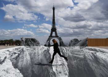 Seorang wanita berpose untuk difoto di lapangan Trocadero di dekat Menara Eiffel tempat seniman dan fotografer Prancis yang dikenal sebagai JR memamerkan karya seninya di Paris, Prancis, pada 21 Mei 2021. (Xinhua/Gao Jing)