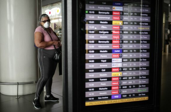 Seorang wanita yang mengenakan masker memeriksa informasi penerbangan di Bandar Udara Internasional El Dorado, di Bogota, Kolombia, pada 16 Maret 2020. (Xinhua/Jhon Paz)