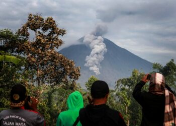 Warga menyaksikan Gunung Semeru dari Desa Sapiturang di Lumajang, Jawa Timur, pada 7 Desember 2021. (Xinhua/Bayu Novanta)