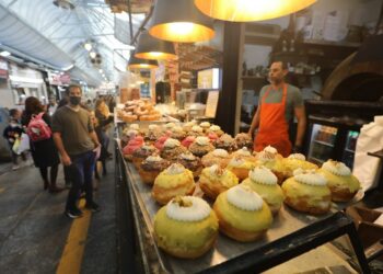 Foto yang diabadikan pada 24 November 2021 ini menunjukkan orang-orang memilih Sufganiyot, donat berisi jeli yang menjadi hidangan tradisional Hanukkah, saat libur Hanukkah umat Yahudi di sebuah toko kue di Yerusalem. (Xinhua/Muammar Awad)