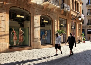 Dua pria yang mengenakan masker berjalan di sebuah kawasan komersial dengan banyak toko masih tutup di pusat kota Beirut, Lebanon, pada 12 Mei 2021. (Xinhua/Liu Zongya)