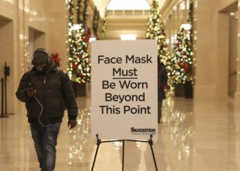 Seorang pria berjalan melewati tanda wajib masker di sebuah gedung di New York, Amerika Serikat (AS), pada 2 Desember 2021. (Xinhua/Wang Ying)