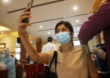 Seorang tenaga kesehatan berswafoto saat menerima satu dosis vaksin Sinovac COVID-19 dari China dalam program vaksinasi massal dengan tenaga kesehatan sebagai kelompok prioritas utama di Surabaya, pada 31 Januari 2021. (Xinhua/Kurniawan)