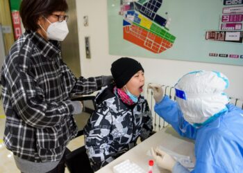 Seorang tenaga kesehatan mengambil sampel usap (swab) dari seorang warga untuk tes asam nukleat di sebuah lokasi pengujian di Manzhouli, Daerah Otonom Mongolia Dalam, China utara, pada 29 November 2021. (Xinhua/Li Zhipeng)