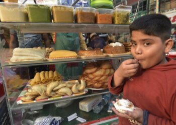 Seorang anak menikmati kue khas musim dingin yang dikenal sebagai "Pitha" di sebuah kios pinggir jalan di Dhaka, Bangladesh, pada 20 Desember 2021. (Xinhua)