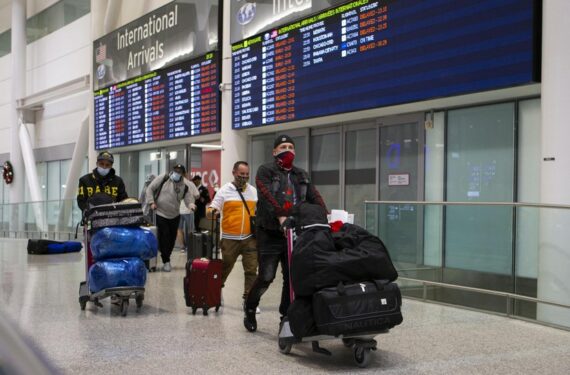 Para pelancong internasional yang memakai masker berjalan keluar dari terminal kedatangan di Bandar Udara Internasional Pearson Toronto di Mississauga, Ontario, Kanada, pada 28 November 2021. (Xinhua/Zou Zheng)
