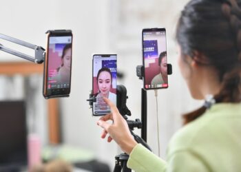Seorang wanita muda menjual pakaian di depan kamera ponsel melalui live streaming di sebuah platform perdagangan elektronik (e-commerce) di Shaxi yang terletak di Kota Zhongshan, Provinsi Guangdong, China selatan, pada 28 Maret 2020. (Xinhua/Liu Dawei)