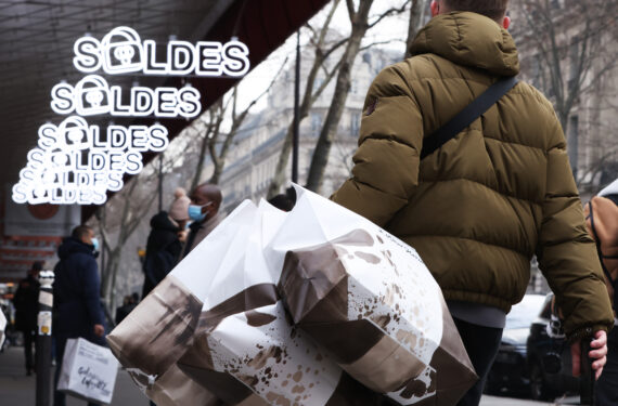 PARIS, Seorang pria yang menenteng beberapa tas belanja berjalan melewati tanda obral musim dingin di luar Galeries Lafayette di Paris, Prancis, pada 12 Januari 2022. Obral musim dingin di Prancis dibuka pada Rabu (12/1) dan akan berlangsung hingga 8 Februari. (Xinhua/Gao Jing)