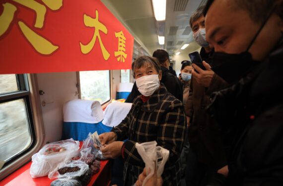 DANDONG, Penumpang membeli barang di kereta No. 4318 di Provinsi Liaoning, China timur laut, pada 15 Januari 2022. Kereta No. 4317 dan 4318 adalah "kereta lambat" yang beroperasi antara Tonghua di Provinsi Jilin dan Dandong di Provinsi Liaoning, China timur laut. Menjelang Tahun Baru Imlek, otoritas perkeretaapian setempat telah mengorganisir pasar di atas kereta yang memungkinkan penduduk desa yang tinggal di sepanjang rute kereta untuk menjual barang kepada penumpang tanpa meninggalkan gerbong kereta. (Xinhua/Yang Qing)