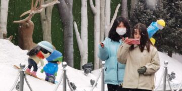 BEIJING, Foto yang diabadikan dengan ponsel pada 20 Januari 2022 ini menunjukkan para pejalan kaki berjalan di tengah hujan salju di sebuah jalan di Beijing, ibu kota China. (Xinhua/Luo Xiaoguang)
