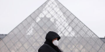 PARIS, Seorang wanita berjalan melewati piramida Museum Louvre di Paris, Prancis, pada 19 Januari 2022. Situasi COVID-19 terus memburuk di Prancis setelah 464.769 kasus baru terdeteksi dalam 24 jam terakhir, seperti diumumkan badan kesehatan masyarakat negara itu pada Selasa (18/1). (Xinhua/Gao Jing)