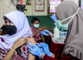 BOGOR, Tenaga kesehatan menyuntikkan vaksin COVID-19 kepada anak-anak dalam program vaksinasi untuk anak usia 6 hingga 11 tahun di Bogor, Provinsi Jawa Barat, pada 26 Januari 2022. (Xinhua/Sandika Fadilah)