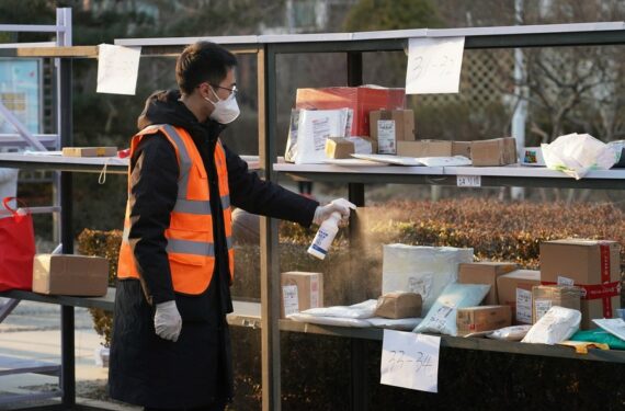 Seorang staf mendisinfeksi parsel-parsel di sebuah komunitas di bawah manajemen tertutup di Beijing pada 18 Januari 2022. (Xinhua/Ren Chao)