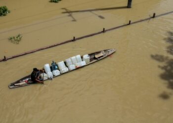 Seorang pria mendayung perahu melintasi banjir di Lhoksukon, Provinsi Aceh, pada 4 Januari 2022. (Xinhua/Fachrul Reza)