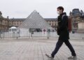Seorang pria berjalan melewati piramida Museum Louvre di Paris, Prancis, pada 19 Januari 2022. (Xinhua/Gao Jing)