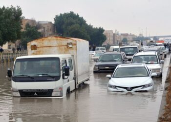 Mobil-mobil menerjang banjir di sebuah jalan di Kegubernuran Farwaniya, Kuwait, pada 2 Januari 2022. (Xinhua)