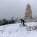 Seorang pria mengendarai sepeda di tengah salju di Athena, Yunani, pada 24 Januari 2022. (Xinhua/Marios Lolos)