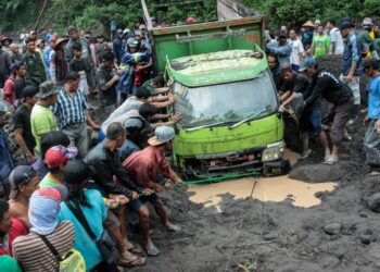 Warga mencoba mengevakuasi kendaraan yang terjebak lahar dingin dari Gunung Merapi di sepanjang Kali Boyong di Kabupaten Sleman, Provinsi Daerah Istimewa Yogyakarta pada 3 Februari 2022. (Xinhua/Priyo Utomo)