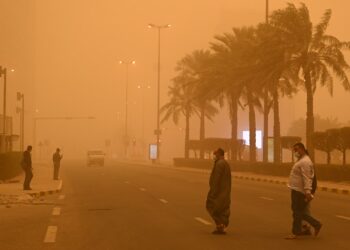 Orang-orang melewati sebuah jalan di tengah debu tebal di Kuwait City, Kuwait, pada 4 Maret 2022. (Xinhua/Asad)