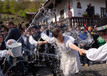 HOLLOKO, Beberapa pria setempat menyiramkan air ke seorang wanita sebagai bagian dari perayaan Paskah tradisional di Holloko, sebuah desa Warisan Dunia, di Hongaria pada 18 April 2022. (Xinhua/Attila Volgyi)