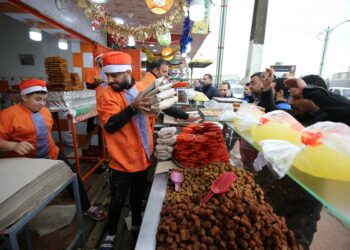 Foto yang diabadikan pada 6 April 2022 ini menunjukkan sejumlah orang membeli makanan penutup tradisional selama bulan suci Ramadan di Boufarik, Aljazair. (Xinhua)