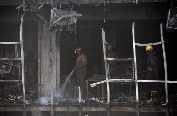 NEW DELHI, Seorang petugas pemadam kebakaran (depan) menyiram puing-puing bangunan komersial yang hangus setelah kebakaran besar di New Delhi, India, pada 14 Mei 2022. Sedikitnya 27 orang tewas dan 12 lainnya mengalami luka bakar akibat kebakaran besar yang terjadi di sebuah bangunan komersial tiga lantai di ibu kota India itu, kata perwira polisi senior Sameer Sharma pada Sabtu (14/5). (Xinhua/Javed Dar)