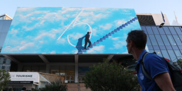 CANNES, Seorang pria berjalan melewati sebuah poster di luar Palais des Festival menjelang Festival Film Cannes ke-75 di Cannes, Prancis selatan, pada 16 Mei 2022. Festival Film Cannes ke-75 rencananya akan digelar mulai 17 sampai 28 Mei. (Xinhua/Gao Jing)