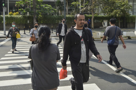 JAKARTA, Sejumlah warga melintas di sebuah jalan di Jakarta pada 18 Mei 2022. Karena jumlah kasus COVID-19 menunjukkan tren penurunan selama beberapa pekan terakhir, pemerintah pada Selasa (17/5) mengumumkan penggunaan masker tidak lagi wajib di luar ruangan. (Xinhua/Veri Sanovri)
