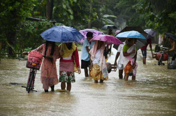 NAGAON, Warga desa berjalan melintasi jalan yang tergenang banjir di Distrik Nagaon, Negara Bagian Assam, India timur laut, pada 17 Juni 2022. (Xinhua/Str)