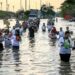 SEMARANG, Orang-orang berjalan mengarungi genangan banjir yang dipicu oleh tingginya air pasang laut di Pelabuhan Tanjung Emas di pesisir Semarang, Provinsi Jawa Tengah, pada 20 Juni 2022. (Xinhua/Rahman Indra)