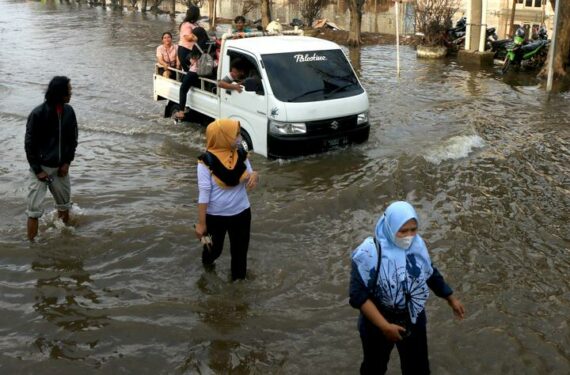 SEMARANG, Sejumlah orang melintasi banjir akibat air pasang di Pelabuhan Tanjung Emas di pesisir Semarang, Provinsi Jawa Tengah, pada 21 Juni 2022. (Xinhua/Rahman Indra)