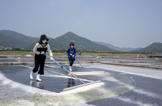 BUAN, Sejumlah orang mendorong kristal-kristal garam dengan alat di sebuah kolam pembuatan garam laut di wilayah Buan, Provinsi Jeolla Utara, Korea Selatan, pada 21 Juni 2022. Terletak di kawasan pesisir, petak-petak kolam garam di wilayah tersebut masih mempertahankan praktik pembuatan garam tradisional. (Xinhua/Wang Yiliang)